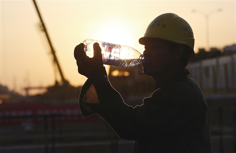 6月3日,在海口市海榆中线附近的市政工程施工现场,建筑工人喝水解暑.